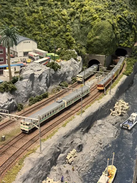 银色模型列车沿着微缩海岸线前行